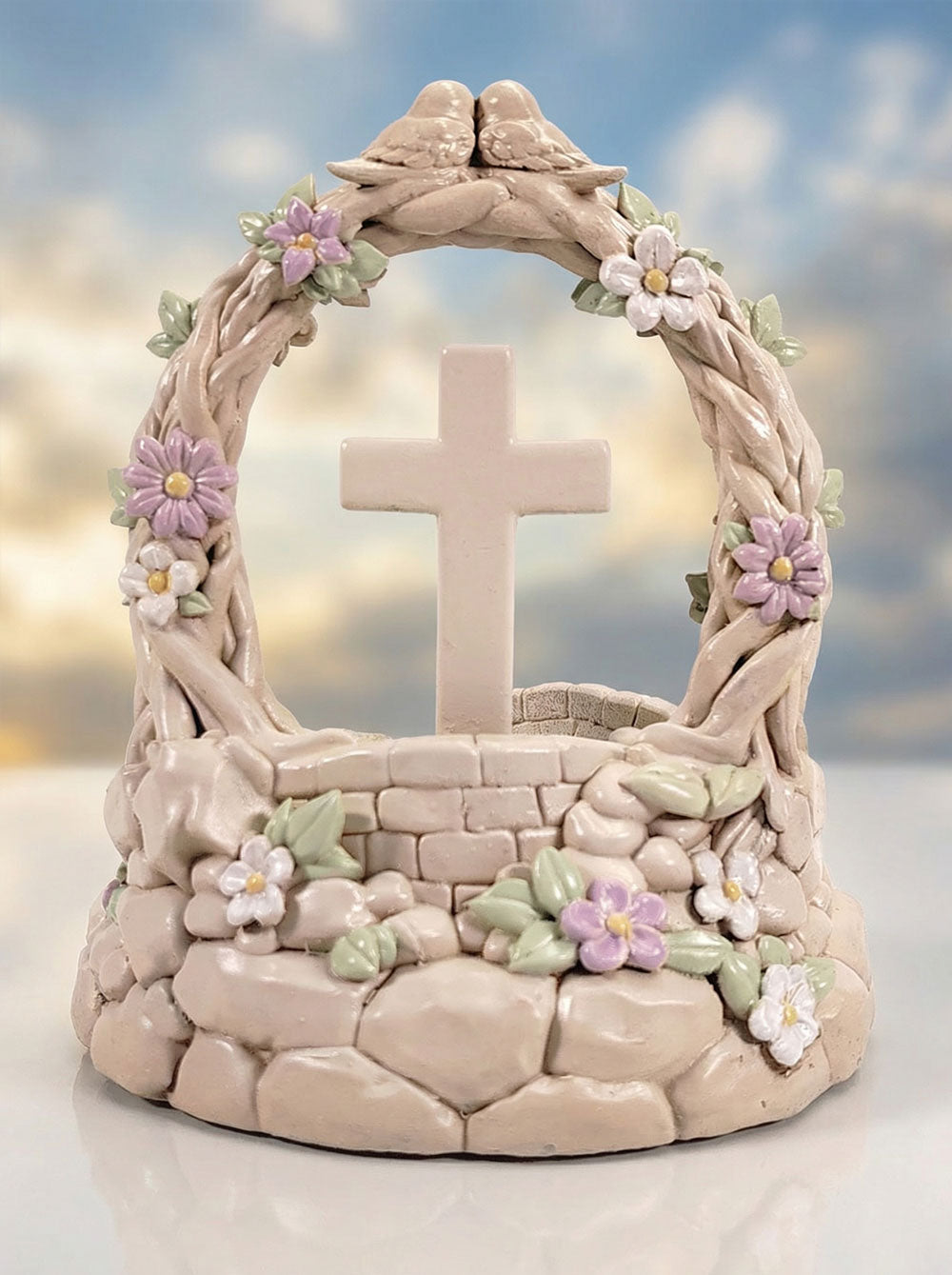 Decorative stone sculpture with a cross and floral elements against a sky background