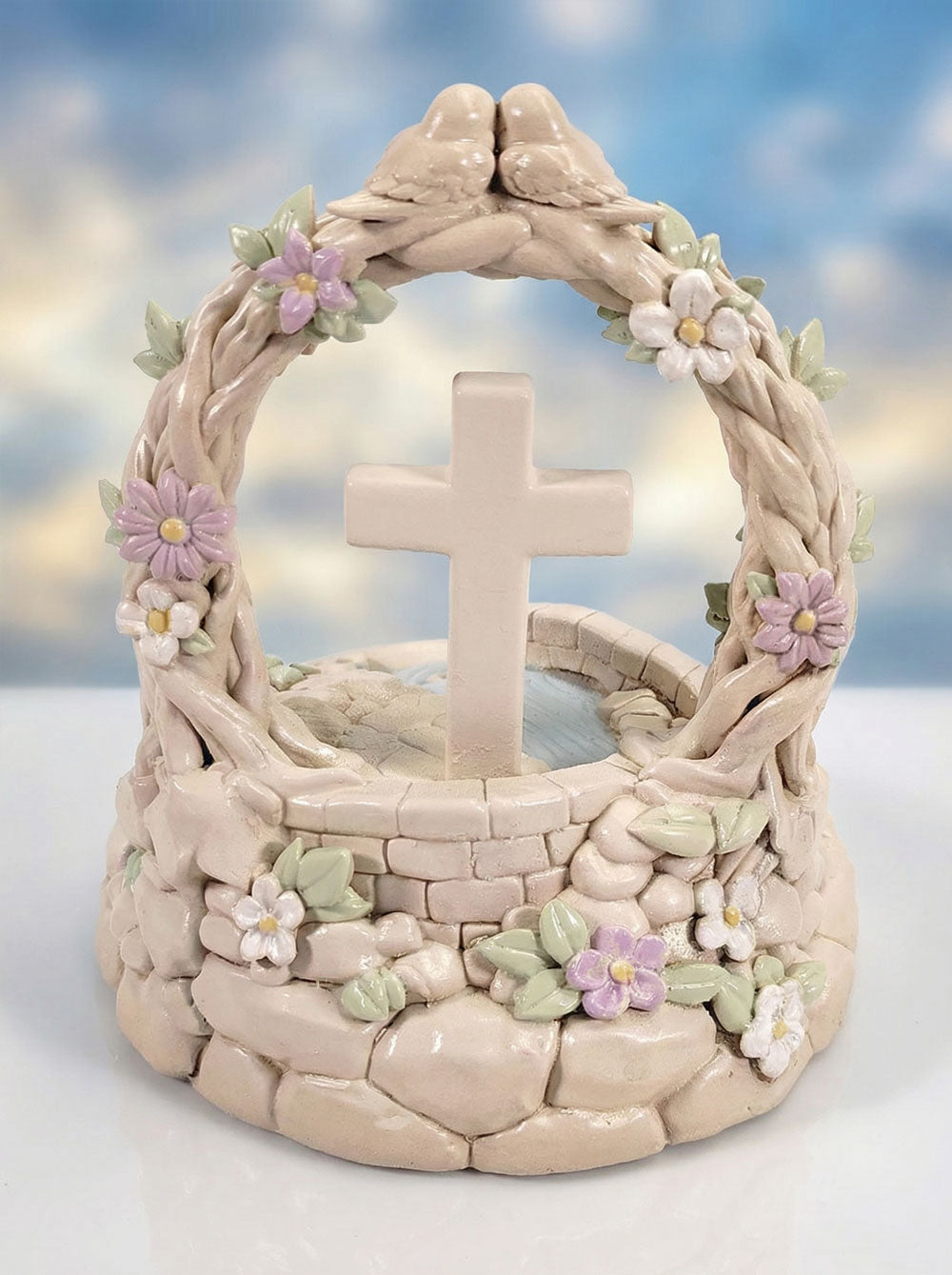Decorative stone sculpture with a cross and floral elements against a blurred natural background